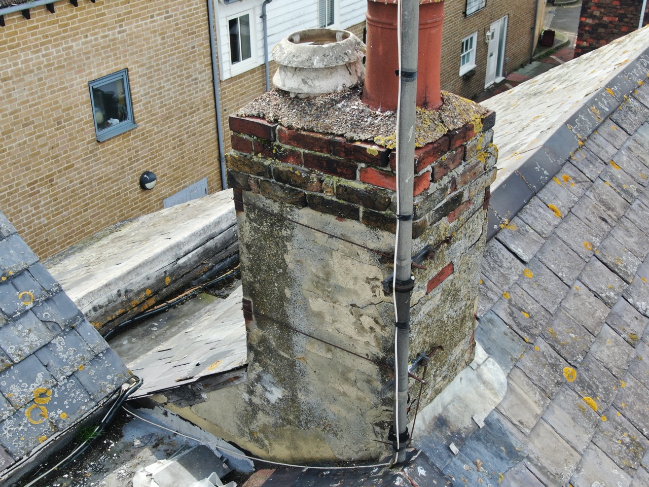 showing off chimney stack damage and high lighting potential problems Close-up drone photograph showing damaged roof tiles and potential leak points on chimney stacks